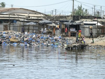 Des habitants enjambent les déchets sur les rives de la lagune Ebrie, au quartier Zimbabwe dans la commune de Portbouet à Abidjan le 22 juillet 2022 - Sia KAMBOU [AFP]