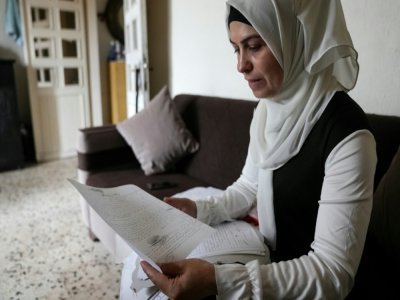 La réfugiée syrienne Ramia al-Sous montre des documents administratifs concernant sa famille dans son appartement dans la plaine de la Bekaa, au Liban, le 13 juin 2022 - DYLAN COLLINS [AFP]