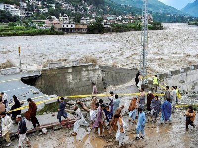 Des personnes se rassemblent devant une route endommagée par les eaux de crue suite aux fortes pluies de mousson dans la région de Madian, dans la vallée de Swat, au nord du Pakistan, le 27 août 2022 - Abdul MAJEED [AFP]