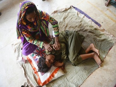 Une femme déplacée et son enfant, qui ont fui les zones touchées par les inondations dans la province de Sindh, se reposent dans une école à Karachi, le 27 août 2022 - Rizwan TABASSUM [AFP]