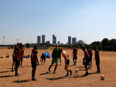 Des hommes s'entraînent au football sur une pelouse désséchée à Londres, le 13 août 2022 - CARLOS JASSO [AFP/Archives]