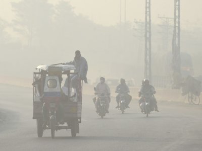 Des Pakistanais se rendent au travail dans la ville de Lahore recouverte d'un épais smog, le 5 juin 2022 - Arif ALI [AFP]