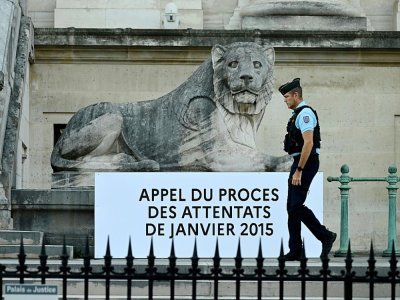 Un gendarme passe devant un panneau apposé devant le palais de justice de Paris, le 12 septembre 2022 - Emmanuel DUNAND [AFP]