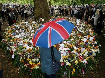 Dans le public attendant l'arrivée du cercueil de la reine Elizabeth II le 13 septembre 2022 à Londres, une personnage s'abrite de la pluie sous un parapluie - CARL DE SOUZA [AFP]