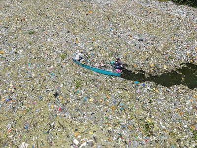 Des habitants ramassent des déchets plastiques et autres qui flottent à la surface du réservoir de Cerron Grande à Potonico, le 9 septembre 2022 au Salvador - Camilo FREEDMAN [AFP]