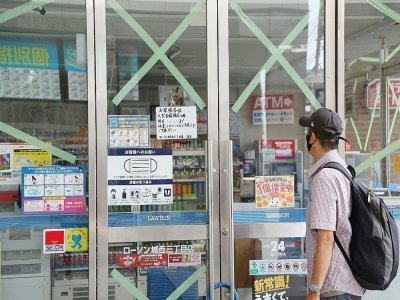 Un homme regarde un avis affiché sur la porte d'un magasin de proximité temporairement fermé à Fukuoka, sur l'île de Kyushu, le 19 septembre 2022 - STR [JIJI Press/AFP]