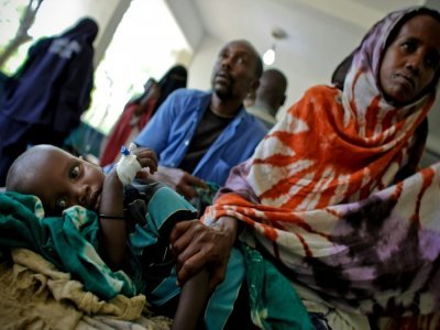 Une mère veille son enfant souffrant de malnutrition à l'hôpital Banadir de Mogadiscio, le 10 août 2011 - STUART PRICE [AU-UN IST/AFP/Archives]