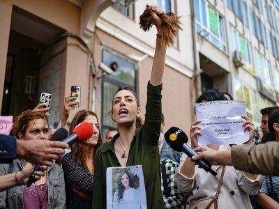 Une Iranienne vivant en Turquie brandit les cheveux qu'elle vient de se couper en protestation après la mort de Mahsa Amini, à Istabul le 21 septembre 2022 - Yasin AKGUL [AFP]