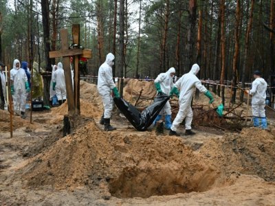 Des enquêteurs dégagent un corps enveloppé dans un sac plastique près d'Izioum, dans l'est de l'Ukraine, le 23 septembre 2022 - SERGEY BOBOK [AFP]
