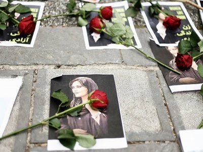 Des roses rouges sur des portraits de Mahsa Amini, morte après avoir été arrêtée par la police des moeurs à Téhéran, déposés devant l'ambassade d'Iran à Bruxelles, le 23 septembre 2022 - Kenzo TRIBOUILLARD [AFP]