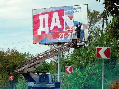 Un homme colle une affiche pour le référendum à Berdyansk, Ukraine, le 26 septembre 2022 - STRINGER [AFP]