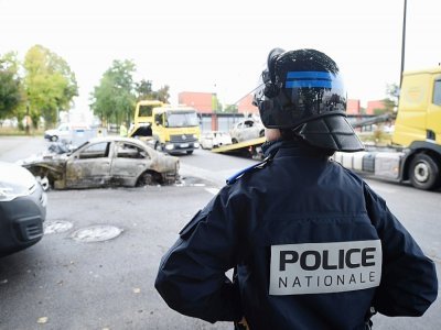 Un policier devant des voitures brûlées lors de violences urbaines, à Alençon, le 28 septembre 2022 - Jean-Francois MONIER [AFP]