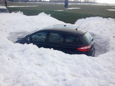 Certains amas de neige sont montés jusqu'à deux mètres de haut. Cette voiture restée stationnée sur un parking en a payé les frais, totalement coincée deux jours après la tempête de neige, le 14 mars 2013. - Sdis14