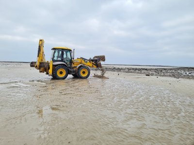 Une tractopelle utilisée pour créer une protection de sable qui va permettre de limiter les projections d'éclats.