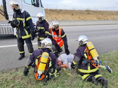 Les pompiers autour du conducteur du poids lourd, inconscient.