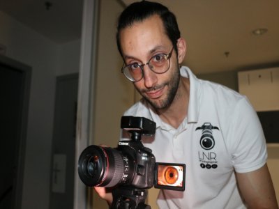 Le photographe Ron Sfez est en pleine session de photographie d'iris dans son studio. Pour que le client ait un aperçu de ses photos, il a incliné l'écran de son appareil photo vers ce dernier. Ensemble, ils choisiront le plus bel iris.