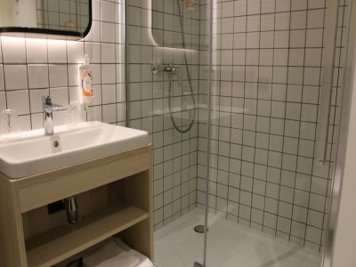 La salle de bain de l'Apart hôtel est aussi composée d'une douche à l'italienne, d'un lavabo et de toilettes, dans un style industriel.