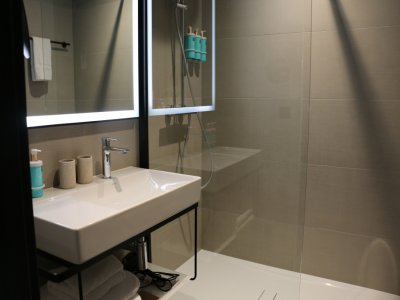 La salle de bain d'une chambre de la partie Novotel comprend toilettes, lavabo et douche à l'italienne.