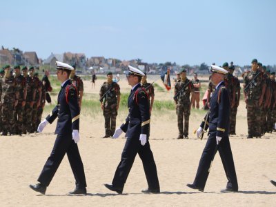 Des hauts gradés marchent devant les rangs militaires, bien en place.