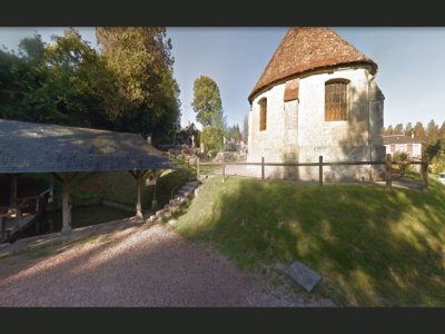 Au premier plan, l'église et le lavoir, puis le cimetière, et finalement la maison qui veille sur ces éléments atypiques.