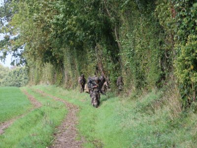 Un groupe de soldat s'est mis en appui le long des haies.