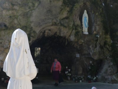 Sainte Bernadette veille sur la grotte, au-dessus de laquelle trône la Vierge Marie.