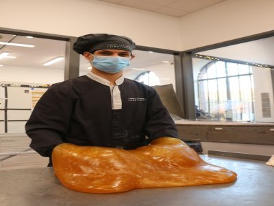 Pour cette troisième étape, Jason Bellion a versé le sucre sur une table en marbre, aidé de ses collègues. Tous munis de spatules et de gants, ils travaillent le sucre pour le faire baisser en température pour le couper.