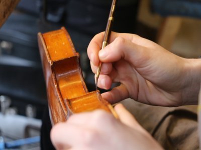 La bonne teinte de vernis trouvée après plusieurs mélanges, la luthière des Violons du Robec de Rouen prend son pinceau. Elle doit être précise, car la couleur des zones à vernir diffère selon leur emplacement.