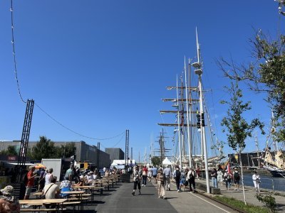 Dès l'ouverture à 10h, le village s'est rapidement rempli de visiteurs se promenant autour des grands voiliers, tandis que d'autres s'installent à une table pour profiter d'un verre au soleil.