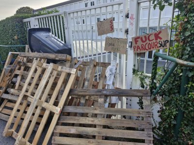 Quelques palettes et poubelles entravent symboliquement les grilles. - Célia Caradec